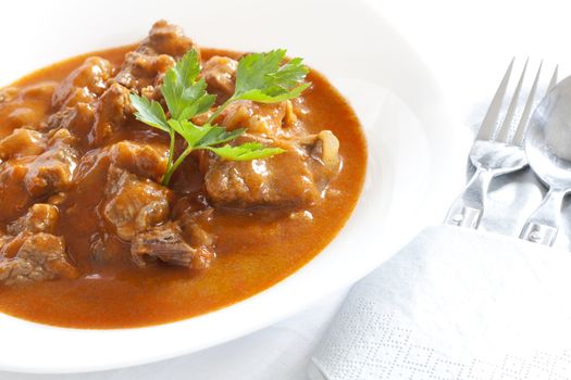 Goulash stew with parsley served in white bowl