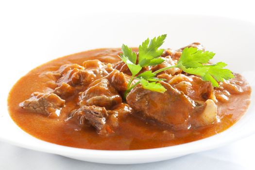 Goulash stew with parsley served in white bowl