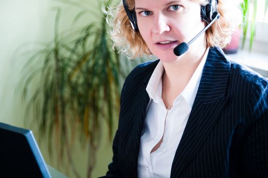 Closeup of a business woman using a laptop and talking into headset