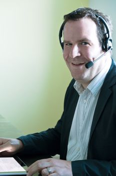 Closeup of a businessman using a tablet pc and talking into headset