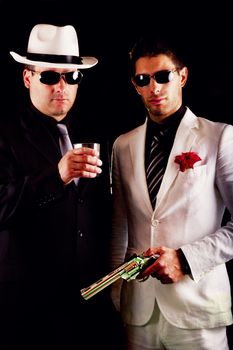 View of two gangster males holding a gun on a black background.