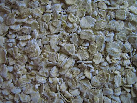 A photograph of uncooked oatmeal detailing its texture.
