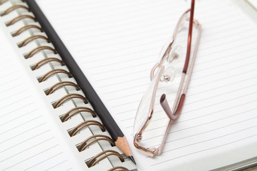 Ruled diary, black pencil and reading glasses