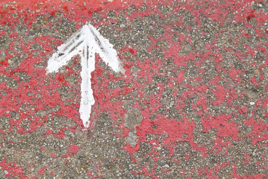 White painted arrow on reddish and gray asphalt