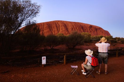 ULURU. AUSTRALIA. 2006 DECEMBER  29:  Tourists at a dawn at mountain. Tourists observe a dawn. Monolith Uluru in the first beams of the sun.. Northern territory. Australia. On December 29 2006.