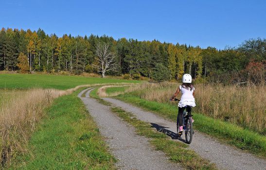 A young girl riding her mountainbike at a gravel road in swedish rural environment.