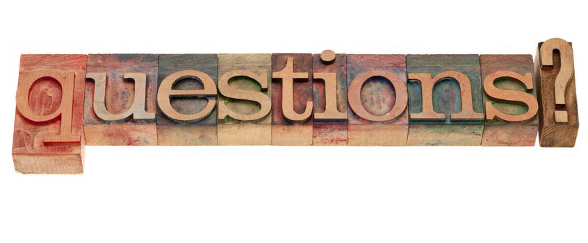 Questions? A word in vintage wooden letterpress printing blocks, stained by color inks, isolated on white