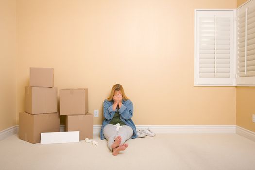 Upset Woman with Tissues on Floor Next to Boxes and Blank Sign in Empty Room.