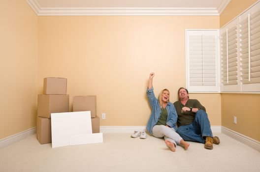 Excited Couple Relaxing on Floor Near Boxes and Blank Real Estate Signs in Empty Room