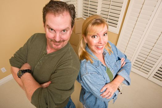 Smiling Goofy Couple and Moving Boxes in Empty Room.