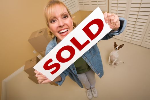 Excited Woman and Doggy with Sold Real Estate Sign Near Moving Boxes in Empty Room Taken with Extreme Wide Angle Lens.
