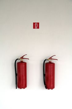two red fire extinguishers on white wall 