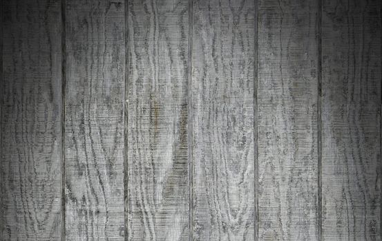 Weathered gray wooden barn siding using vertical planks lit dramatically from above