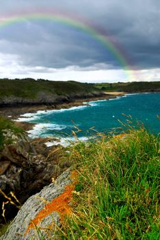 Landscape of rocky Atlantic coast in Brittany France with stormy sky and rainbow