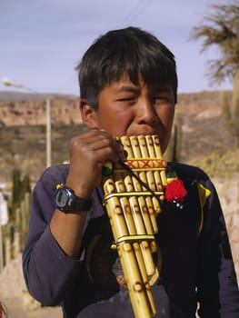 indigenous boy touching to called wind instrument quena