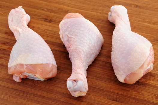 Raw chicken drumsticks on a wooden cutting board