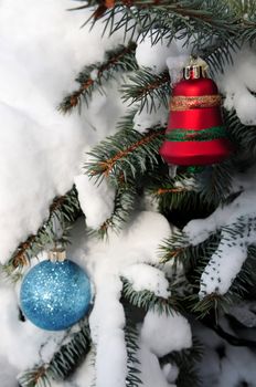 Christmas ornaments hanging on snow covered spruce tree outside