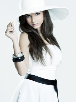 Beautiful and fashion young woman posing and wearing a wonderful white dress with a white hat