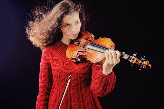 Young woman holding a violin. Isolated on the black background