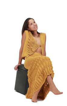 Young relaxed woman sitting on a stool,isolated against a white background.