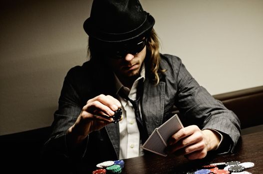 Man with hat and glasses playing underground poker.