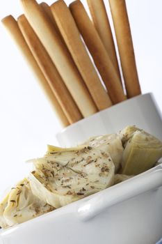 Healthy appetizer consisting of herbed artichoke hearts with bread sticks.