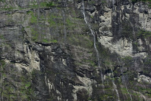 Rocky coastline of fjord with lot of springs and waterfalls in Geiranger, Norway