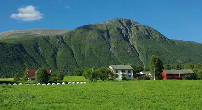 Beautiful Norway rural landscape with mountain peaks and farm