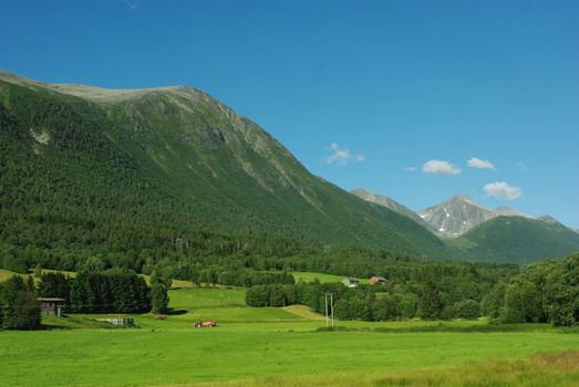 Beautiful Norway rural landscape with mountain peaks and farm