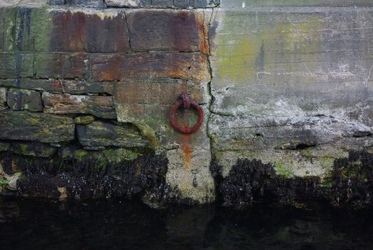 Old rusty iron ring for tying a boat at the pier