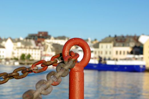 Old rusty fence made of chain on sea embankment