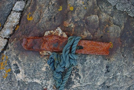 Old rusty iron fixture for tying a boat at the pier