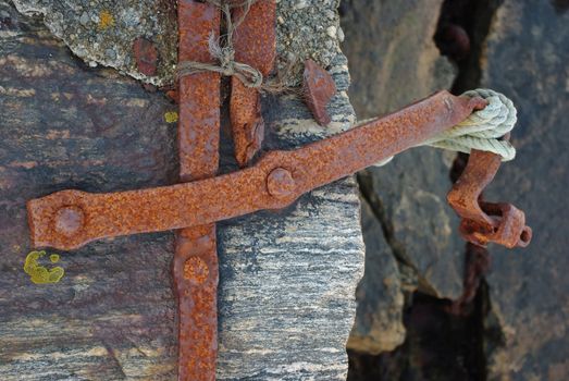 Old rusty iron fixture for tying a boat at the pier
