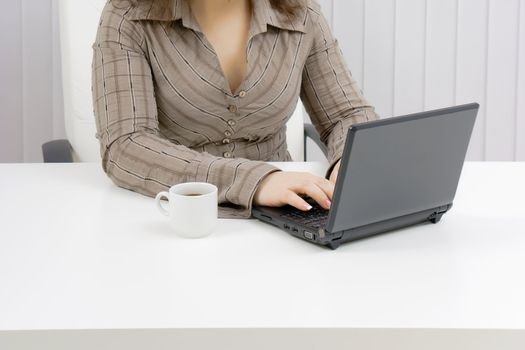 girl with a laptop works in an office. Part of the body
