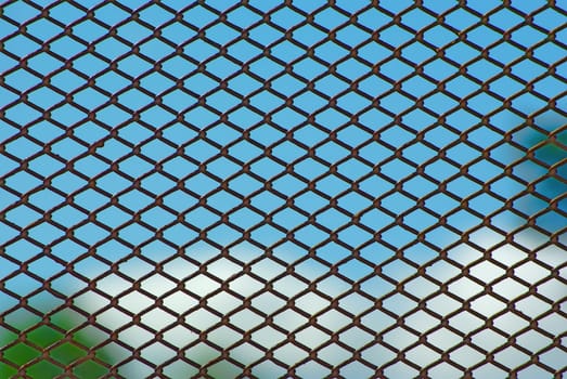 Chain link rusty fence on a blue sky background