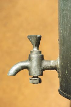 Old silumin water tap on rusty tank