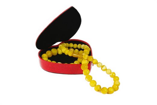 Amber beads in heart form gift box on white background