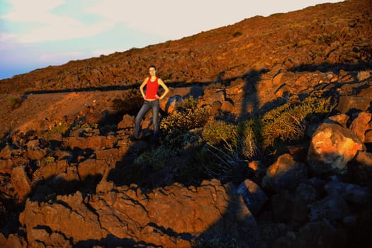 The girl in mountains at a dawn. Early morning, the girl on a slope of stony mountain.