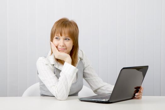 Attractive relaxed and smiling girl with a laptop in the office
