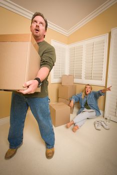 Stressed Man Moving Boxes for Demanding Wife Surrounded by Other Boxes.