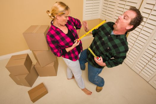 Couple Having a Fun Sword Fight with Their Tape Measures Surrounded by Packed Moving Boxes.