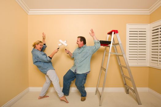 Fun Couple Playing Sword Fight with Paint Rollers in Room - Ladder and Paint Tray Near.