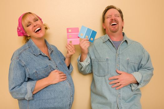 Laughing Man and Pregnant Woman Deciding on Pink or Blue Wall Paint with Swatches in Hand.
