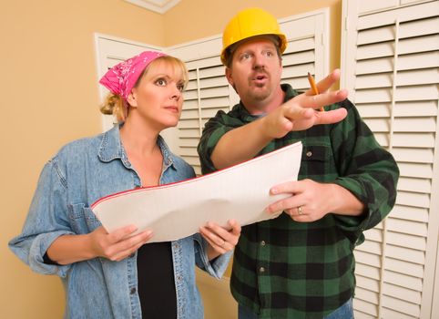 Male Contractor in Hard Hat Discussing Plans with Woman in Room.