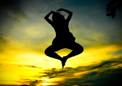 Silhouette of a happy woman jumping at sunset