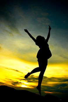 Silhouette of a happy woman jumping at sunset