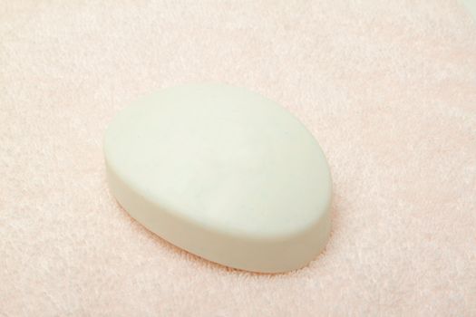 White soap bar on light pink bath towel