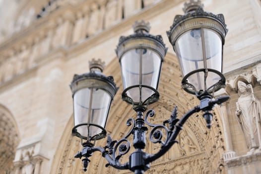 Antique lamp post against the facade of Notre - Dame Cathedral