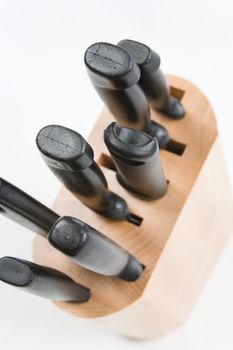 Kitchen knives in a wooden block on a white background