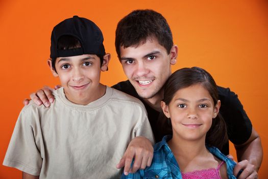 Smiling brothers and sister on an orange background
